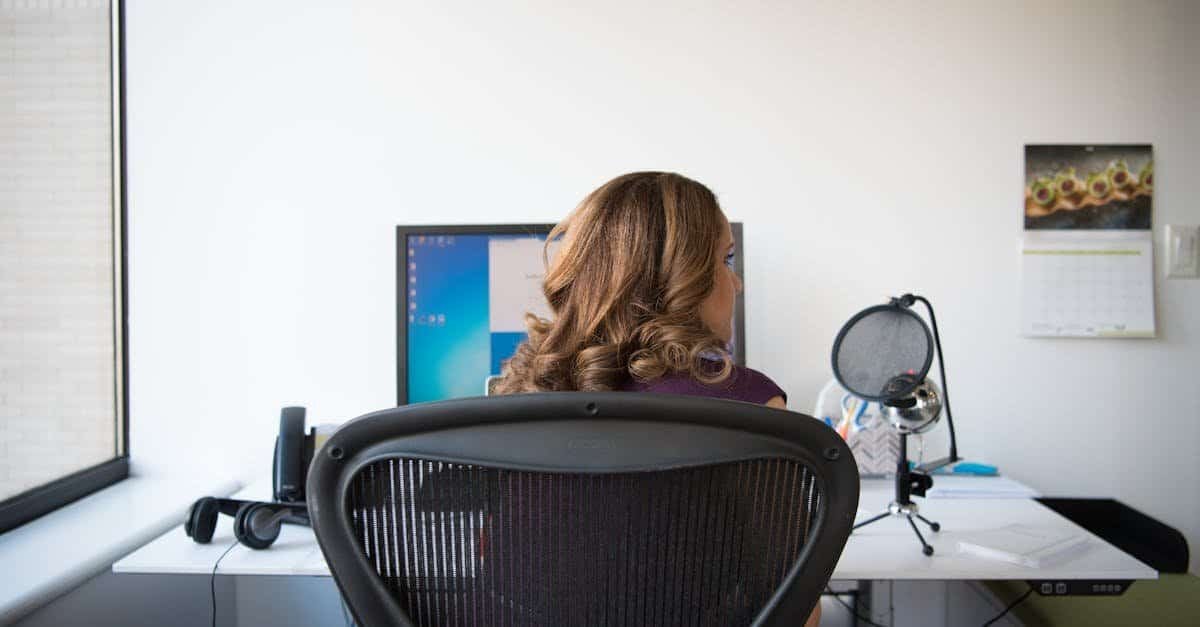Woman working at a modern office desk with computer and accessories.