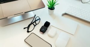 Overhead view of a sleek workspace with a laptop, smartphone, smartwatch, and tech accessories.