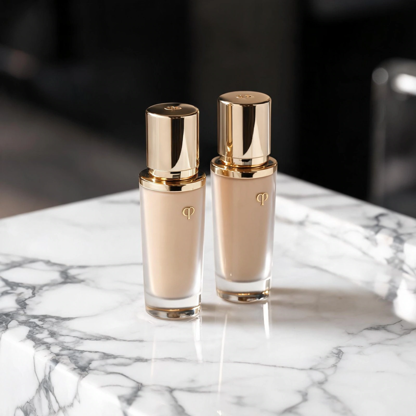 Elegant luxury foundation bottles with gold caps on marble surface.