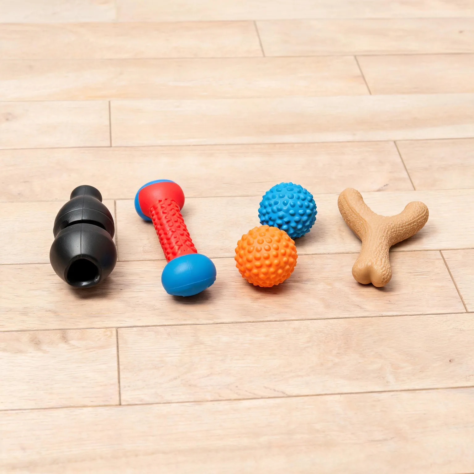 Best dog toys for aggressive chewers 2026: durable rubber and nylon chew toys and fetch balls on a bright wooden floor